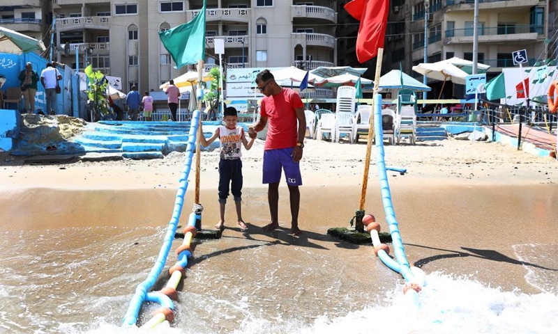 A visually-impaired boy walks with the help of a beach worker at the Mandara beach in Alexandria, Egypt, on July 11, 2022.Photo:Xinhua