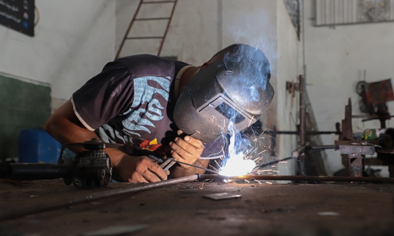 Fakher Hamad, a hearing impaired Palestinian, works on making art from iron at his workshop in Beit Hanoun town in the northern Gaza Strip, on July 18, 2022.(Photo: Xinhua)