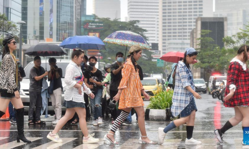 People walk on a zebra crossing like catwalk models at the Dukuh Atas area in Jakarta, Indonesia, July 23, 2022. The Dukuh Atas area in Jakarta has recently become viral among fashion lovers who gather here and show their styles like real models.. Photo: Xinhua