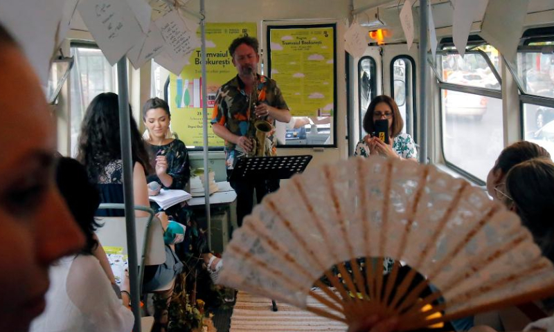 People attend a cultural event called Tramvaiul Bookuresti (Bookarest Tramway) in a vintage tram in Bucharest, capital of Romania, July 23, 2022. Organized by the Cultural Centre of the Townhall, the cultural event is hosted in a vintage tramway where people could listen to poetry, music and historic stories about the town during a two-hour trip.  Photo: Xinhua