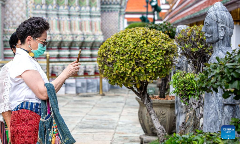 A tourist takes photos of stone statues at Wat Phra Kaew temple of the Grand Palace in Bangkok, Thailand, July 20, 2022. (Xinhua/Wang Teng)