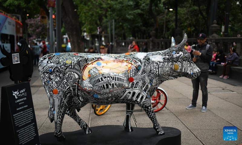A man takes photos of a cow sculpture displayed during the CowParade event in Mexico City, Mexico, July 24, 2022. (Xinhua/Xin Yuewei)