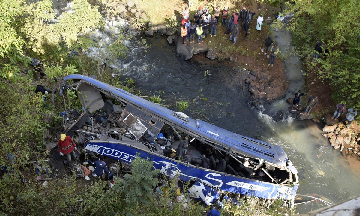 People look at the wreckage of a bus in Tharaka Nithi County, Kenya on July 25, 2022. Thirty people were killed when the bus plunged off a bridge about 40 meters into the Nithi River valley below on July 24. Twenty people died on the spot, while four died in hospital and another six bodies were recovered on July 25. Photo: AFP