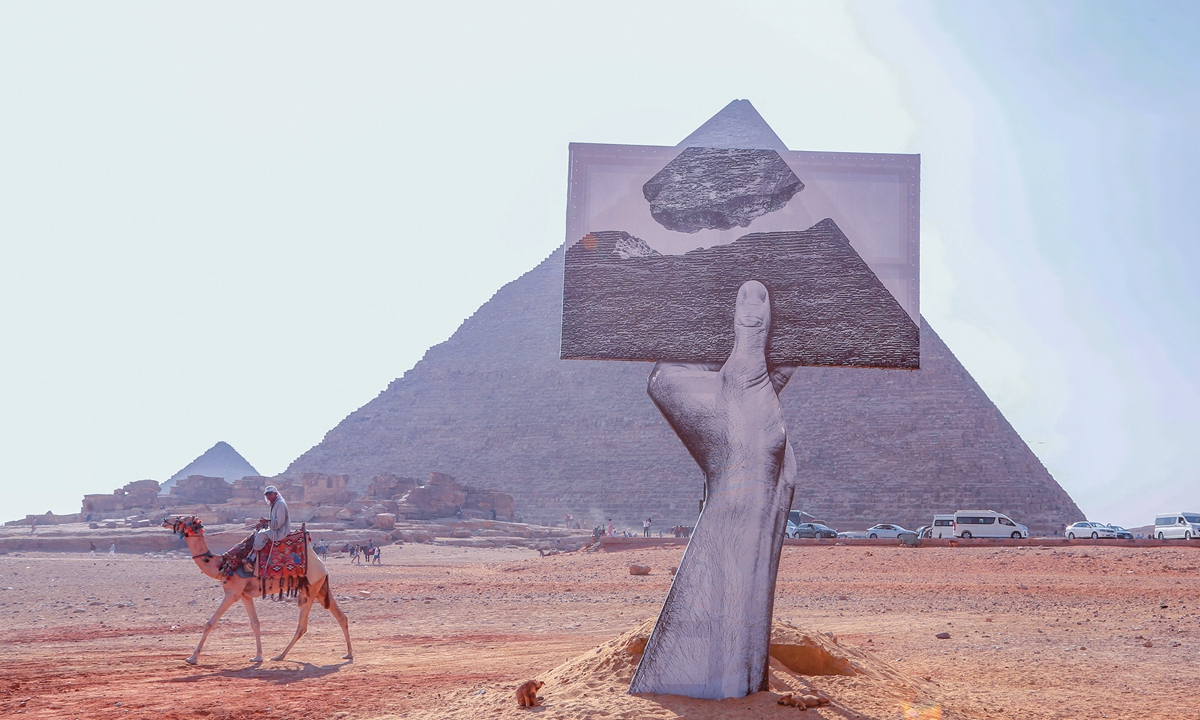 A man on camelback rides past installation work Greetings from Giza at the Great Pyramids of Giza on October 25, 2021 in Giza, Egypt. The work was presented by Art D'Egypte. Photo: IC