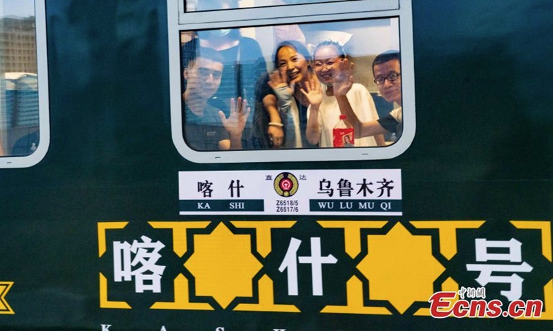 2022 年 7 月 25 日，中国西北部新疆维吾尔自治区的首列直达卧铺列车上，乘客挥手离开乌鲁木齐。（照片：中新社/张山）
