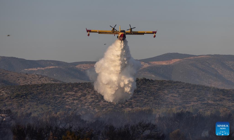 An aircraft tries to extinguish a wildfire in a forest next to Mandra town in western Attica, Greece, on July 26, 2022.(Photo: Xinhua)