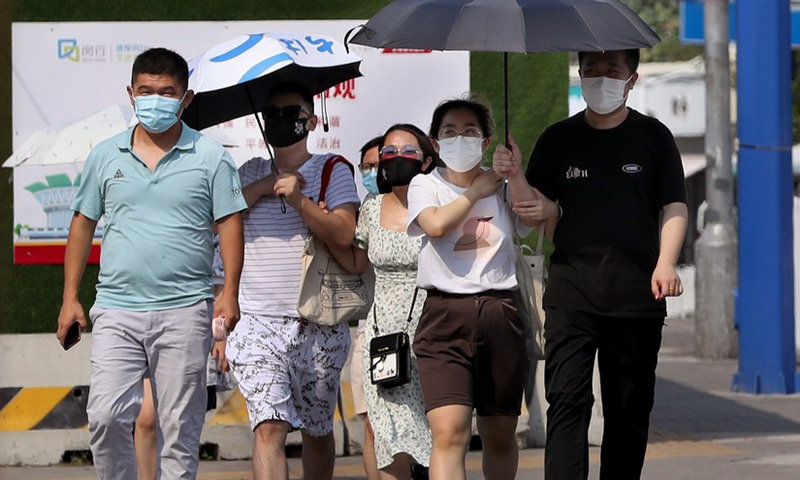 People walk on the street amid high temperature in Minhang District of east China's Shanghai, July 10, 2022.Photo:Xinhua