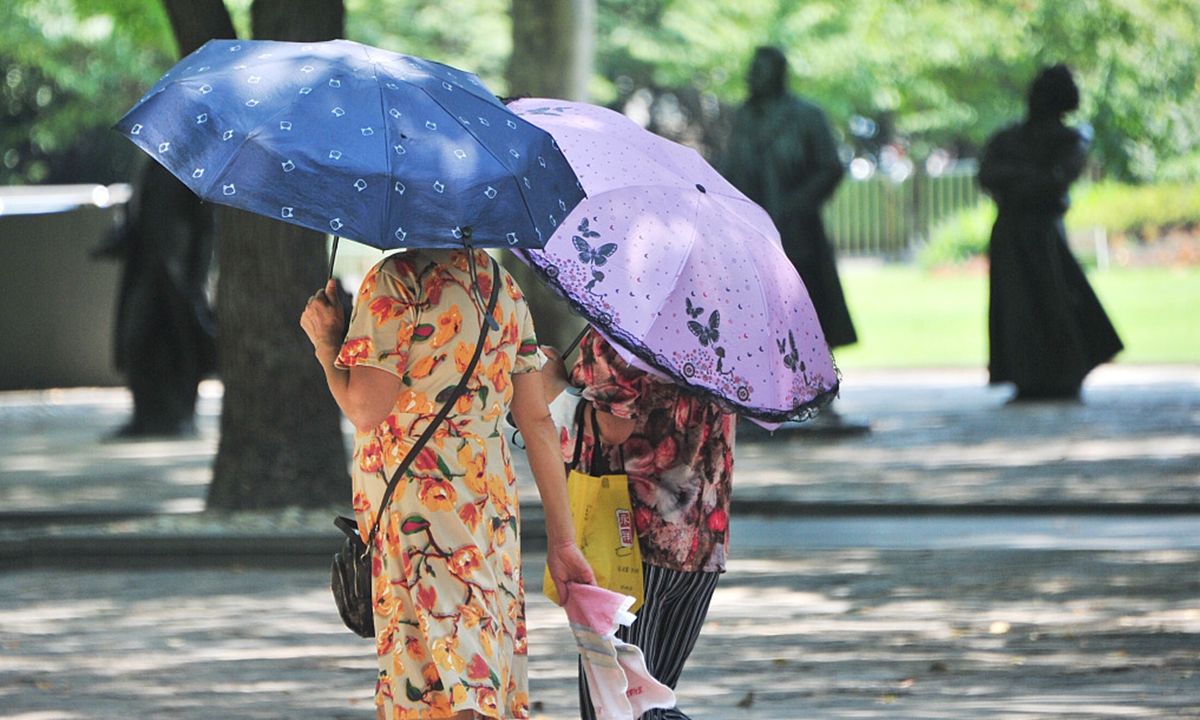 Shanghai residents walk on streets with umbrellas as the city's temperature hits 40 C again on August 11, 2022. Photo: IC