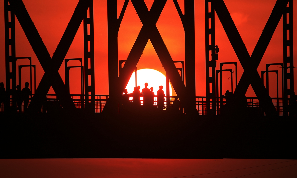 Residents in Harbin, Northeast China's Heilongjiang Province stand on the Binzhou Bridge above Songhua River in the city as the sun sets. Photo: IC