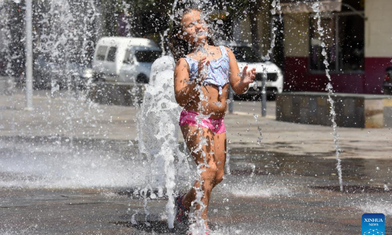 A girl plays at a fountain to cool off in Coria, Spain on July 30, 2022. Photo: Xinhua