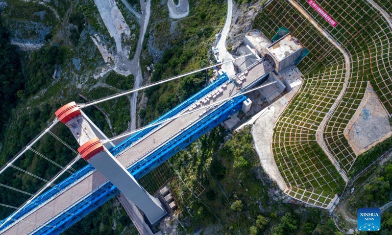 Aerial photo taken on July 26, 2022 shows the Jinsha River grand bridge linked with the entrance of the Haba Snow Mountain tunnel along the Lijiang-Shangri-La railway in southwest China's Yunnan Province. With a designed speed of 120 kilometers per hour, the 140-kilometer Lijiang-Shangri-La railway is expected to shorten the travel time between Lijiang and Shangri-La after its operation.(Photo: Xinhua)