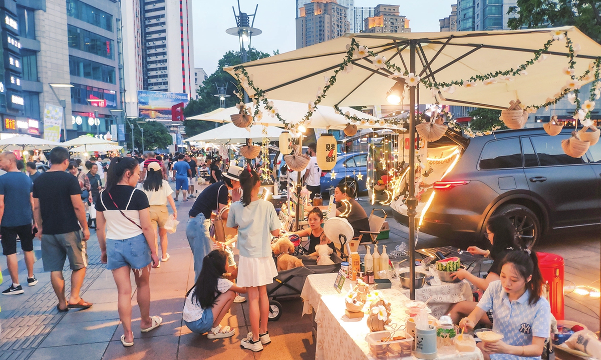 A trunk bazaar opens for business in front of a mall in Jiulongpo district in Southwest China's Chongqing Municipality, on July 30, 2022. Over 20 vehicles took part in the market, their trunks filled with different merchandise, lighting up the city's night life.Photo: VCG