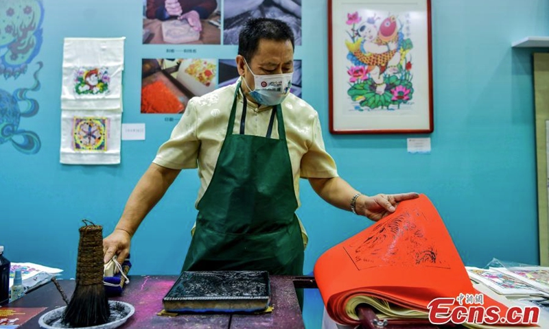 An inheritor creates Wuqiang woodblock new year painting during an intangible cultural heritage exhibition in Xinjiang Art Museum, Urumqi, northwest China's Xinjiang Uyghur Autonomous Region, July 31, 2022. (Photo: China News Service/Liu Xin)