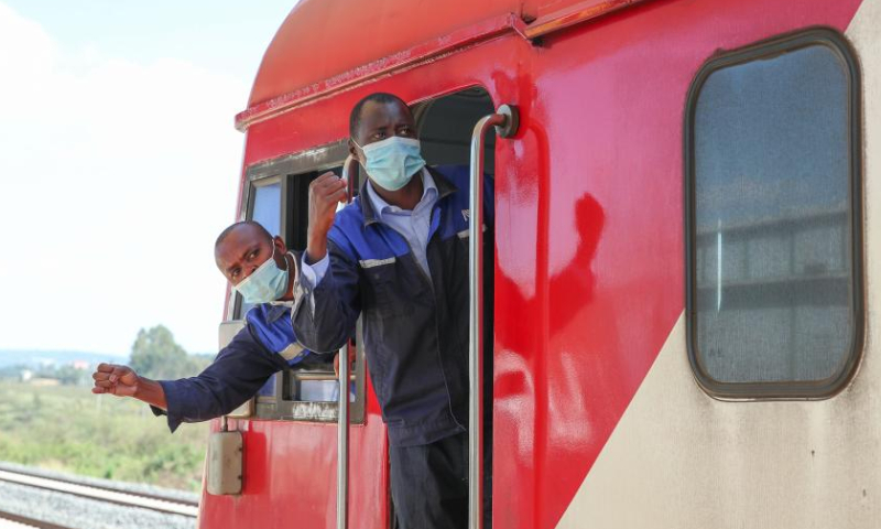 Kenyan drivers John Pius (L) and Brian Kemboi confirm safety with platform staff at Ngong station in Kajiado, Kenya, March 25, 2022. Launched on May 31, 2017, the 480 km Mombasa-Nairobi Standard Gauge Railway (SGR), financed mainly by China and constructed by China Road and Bridge Corporation (CRBC), has fostered job creation for local people. Photo: Xinhua