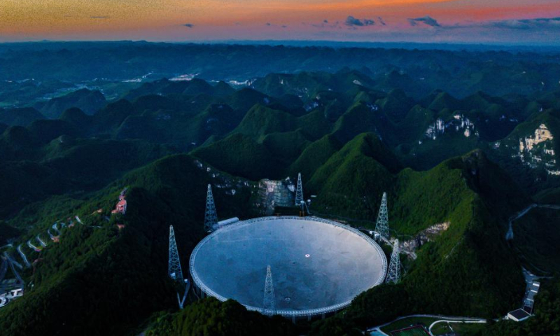 Aerial photo taken on July 21, 2022 shows China's Five-hundred-meter Aperture Spherical Radio Telescope (FAST) under maintenance at sunset in southwest China's Guizhou Province. Located in a naturally deep and round karst depression in southwest China's Guizhou Province, FAST started formal operation in January 2020 and officially opened to the world on March 31, 2021. It is believed to be the world's most sensitive radio telescope. With FAST, scientists have identified over 660 new pulsars. (Xinhua/Ou Dongqu)