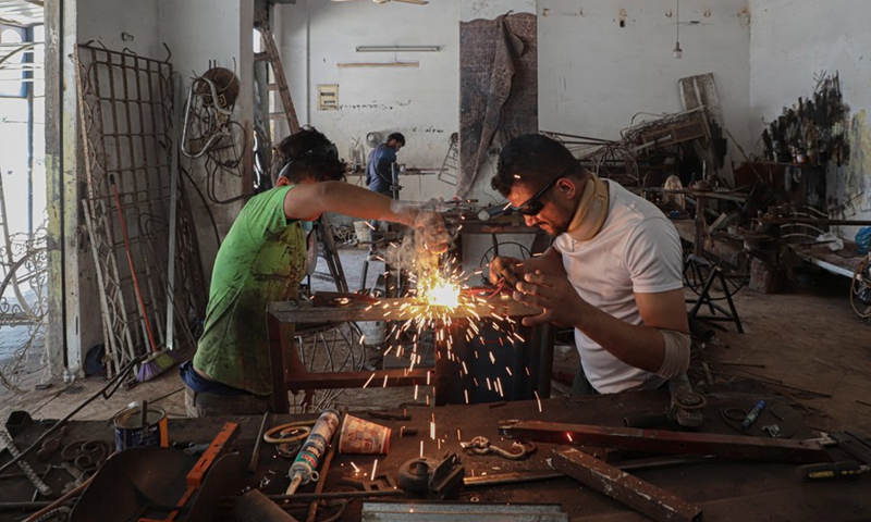 Palestinian hearing impaired Fakher Hamad (R) works inside his small workshop in Gaza City, on Aug. 2, 2022. (Photo: Xinhua)