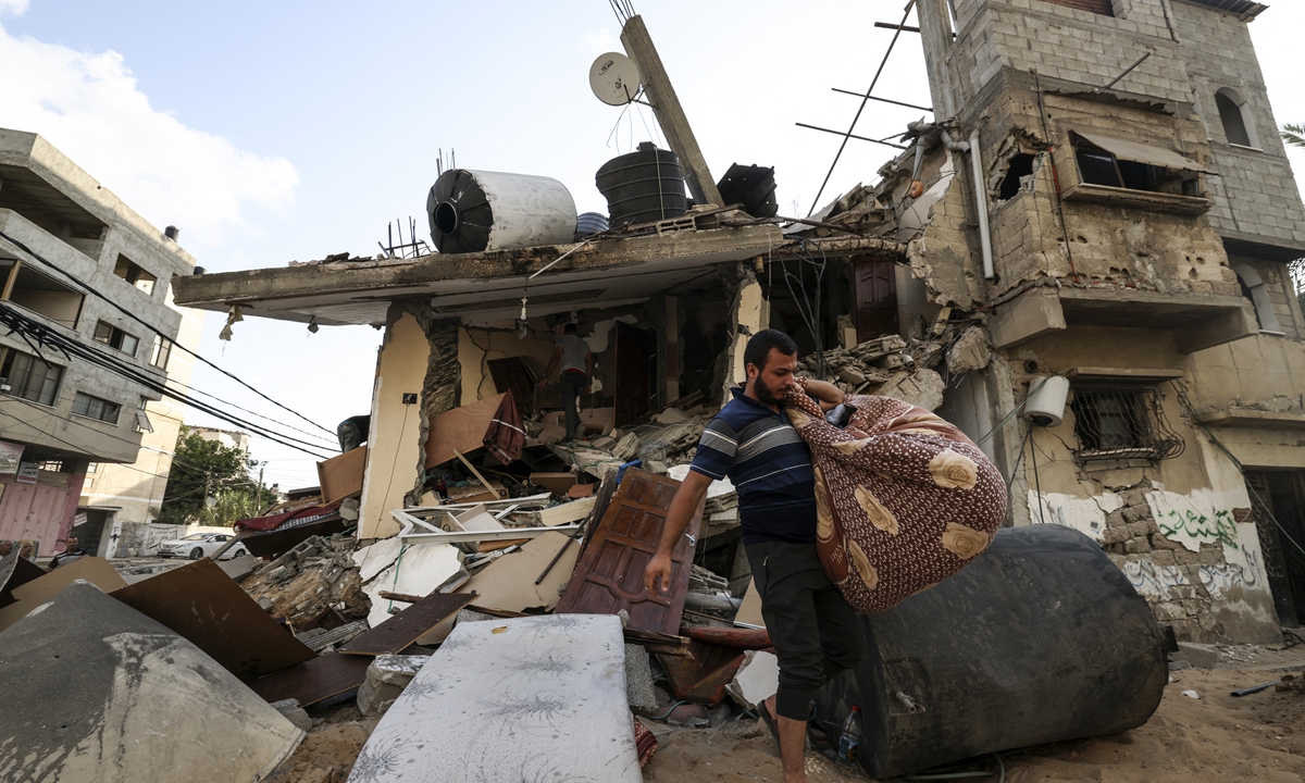 Palestinians salvage belongings from the rubble of their home, following Israeli air strikes in Gaza City, on August 7, 2022. Photo: AFP