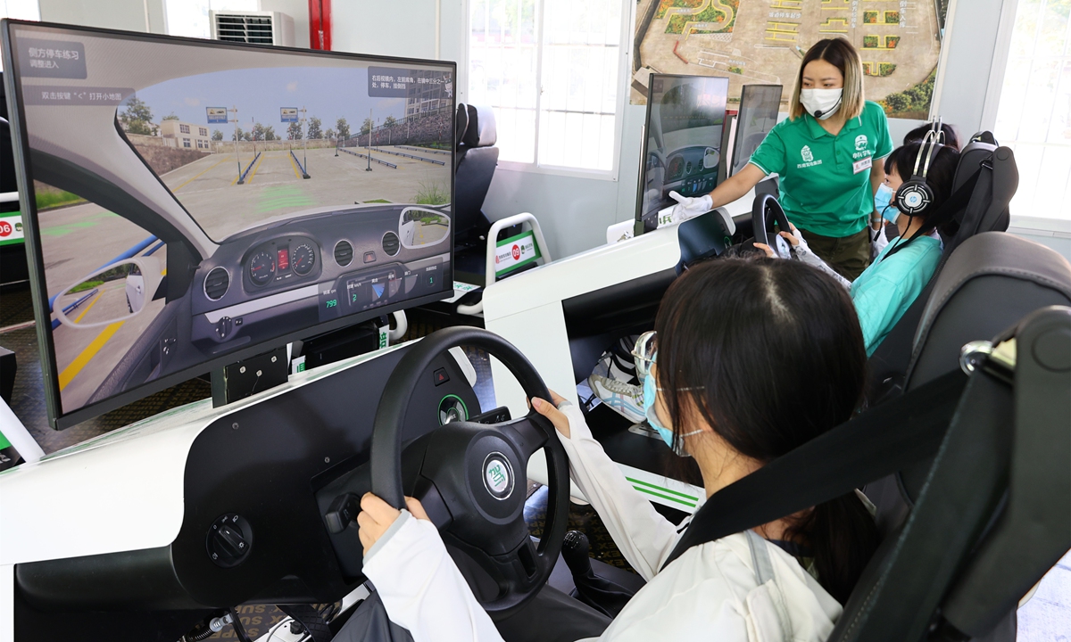Students learn to drive on an artificial intelligence (AI) simulator at a driving school in Southwest China's Chongqing Municipality on August 9, 2022. The school uses AI simulators and robot coaches to assist teaching. The simulated driving scene is 100 percent like the real scene. Photo: VCG