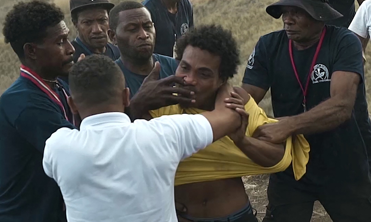 This screen grab made from a video taken and released by Mannar Levo shows security officials restraining a man (yellow shirt) who attacked a Japanese sailor with scissors during a World War II memorial ceremony to mark the 80th anniversary of the Battle of Guadalcanal, in Honiara on the Solomon Islands on August 8, 2022. Photo: VCG