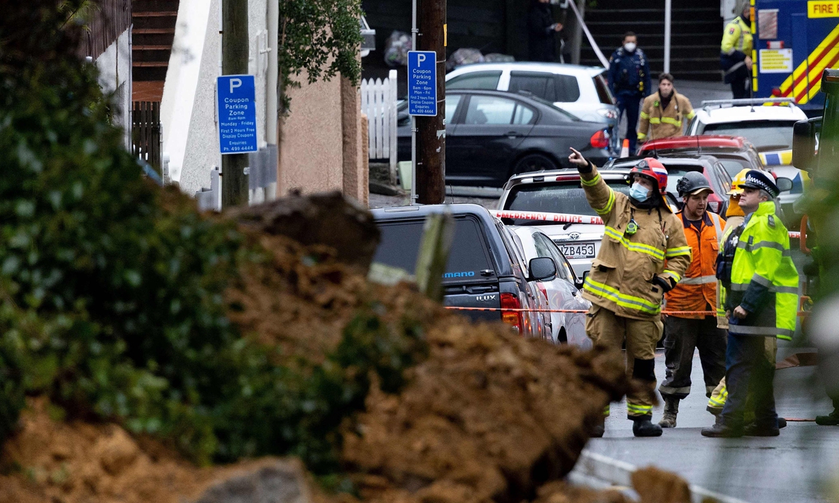 A firefighter points at a landslip area caused by heavy rainfall during a storm in Wellington, New Zealand on August 8, 2022. Photo: VCG