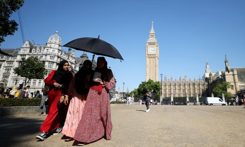 People walk on the lawn in Parliament Square in London, Britain, on Aug. 13, 2022. A drought was officially declared on Friday across a large swathe of England, amid a new heatwave and prolonged dry weather.  Photo: Xinhua