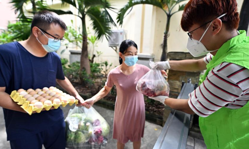 A volunteer (1st R) delivers daily life supplies at the entrance to a residential compound in Sanya, south China's Hainan Province, Aug. 13, 2022.  Photo: Xinhua