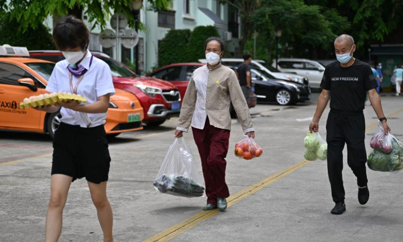 Staff members of the property management service (L and C) help a resident (R) move daily life supplies in a residential compound in Sanya, south China's Hainan Province, Aug. 13, 2022.  Photo: Xinhua