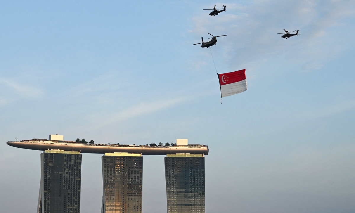 A Singapore Air Force Chinook helicopter escorted by Apache helicopters parade with the flag of Singapore to mark the country's 57th National Day, at Marina Bay in Singapore on August 9, 2022. Photo: AFP