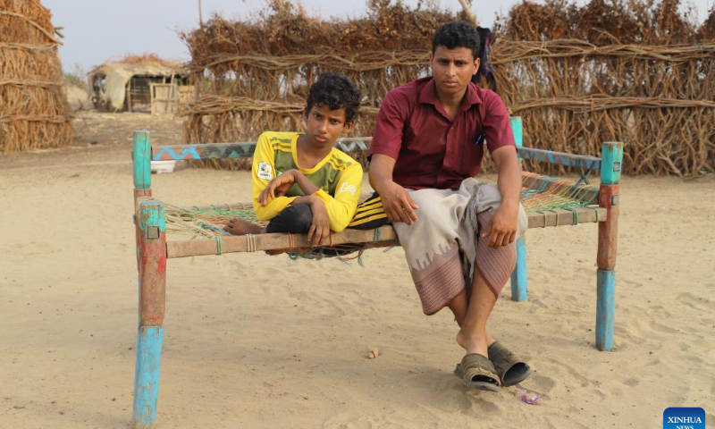 Hasan al-Jaeyedi (L), who was hurt and paralysed by shrapnel from a projectile, sits on a bench with his brother in front of his family's hut in Midi District, Hajjah Province, Yemen, on Aug. 13, 2022. Hasan al-Jaeyedi, a Yemeni boy, has been largely confined to bed since shrapnel from a projectile during a military attack more than six years ago hurt his head and spine and paralysed him. Photo: Xinhua