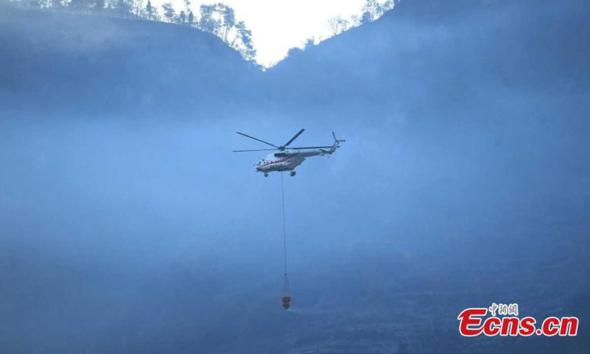 2022 年 8 月 19 日，一架直升机扑灭了重庆市涪陵区的大规模山火。消防员奋力扑灭大火。 图片：中新社