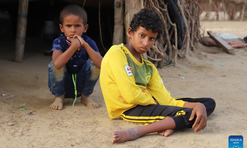 Hasan al-Jaeyedi (R), who was hurt and paralysed by shrapnel from a projectile, sits on the ground in front of his family's hut in Midi District, Hajjah Province, Yemen, on Aug. 13, 2022. Hasan al-Jaeyedi, a Yemeni boy, has been largely confined to bed since shrapnel from a projectile during a military attack more than six years ago hurt his head and spine and paralysed him. Photo: Xinhua