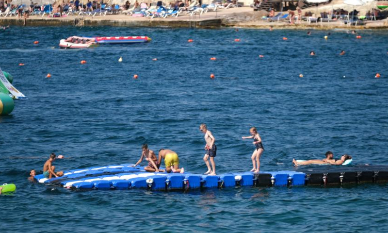 People cool off on Qawra beach, Malta, Aug. 9, 2022. (Photo by Jonathan Borg/Xinhua)
