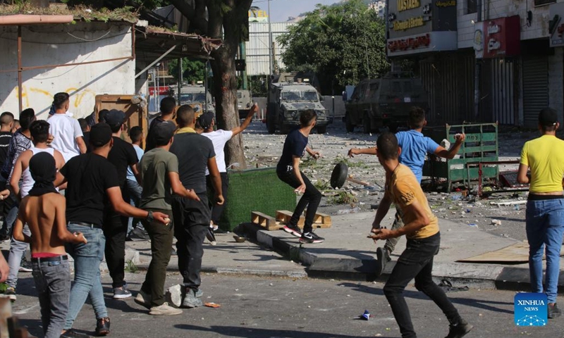 Palestinian protesters hurl stones at Israeli military vehicles during clashes in the West Bank city of Nablus on Aug. 9, 2022. Three Palestinians were killed and 40 others were injured early Tuesday in clashes with the Israeli soldiers in the northern West Bank city of Nablus, Palestinian medics and eyewitnesses said.(Photo: Xinhua)