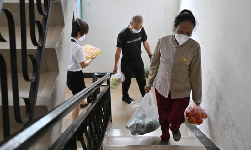 Staff members of the property management service (R and L) help a resident (C) move daily life supplies in a residential compound in Sanya, south China's Hainan Province, Aug. 13, 2022.  Photo: Xinhua