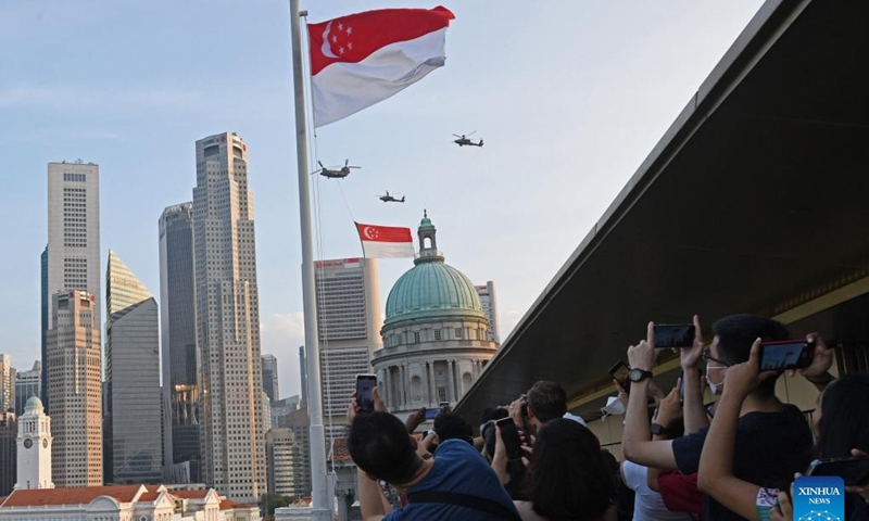 People take photos as a helicopter squadron passes by during the 57th National Day celebrations in Singapore, Aug. 9, 2022.(Photo: Xinhua)