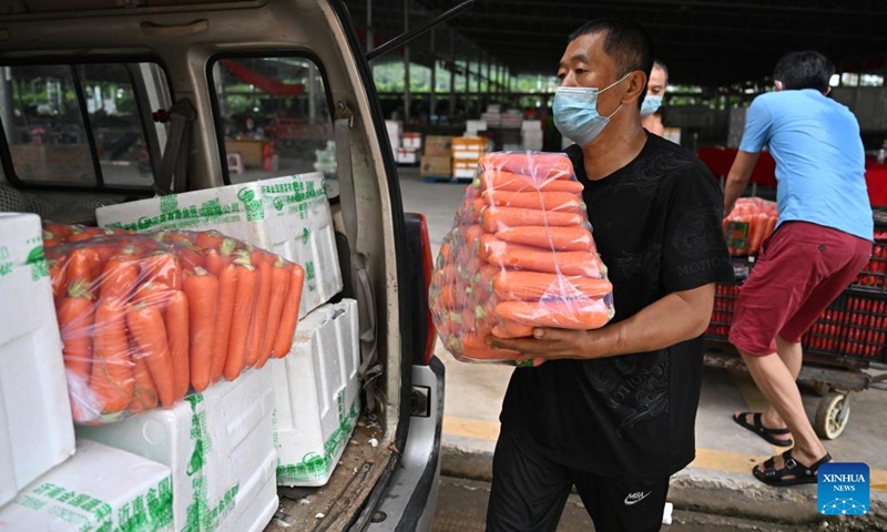 Staff members load vegetables to a vehicle at an agricultural wholesale market in Sanya, south China's Hainan Province, Aug. 8, 2022. Task forces have been established to work around the clock to ensure daily life supplies for local residents and stranded tourists in an effort to fight against the new resurgence of COVID-19 in the city.((Photo: Xinhua)