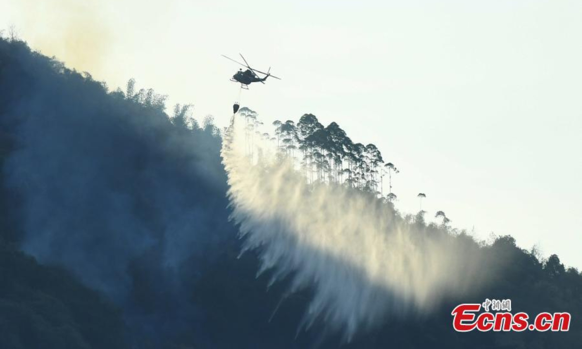 A helicopter extinguishes the massive mountain fire in Fuling district of Chongqing, Aug 19, 2022. Firefighters battle to contain the blaze. Photo:China News Service
