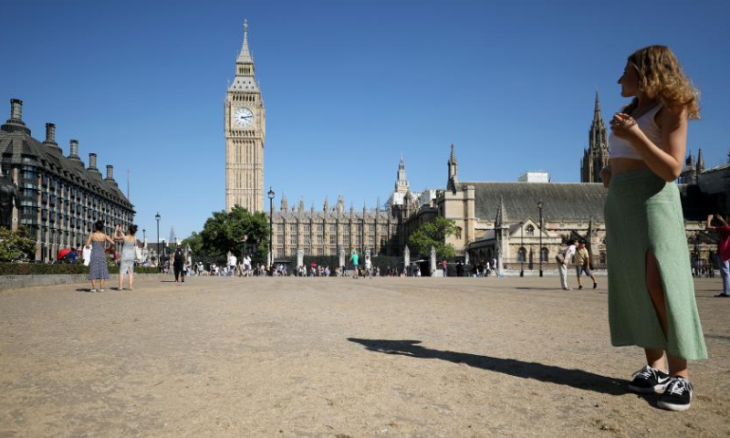 A woman stands on the lawn in Parliament Square in London, Britain, on Aug. 13, 2022. A drought was officially declared on Friday across a large swathe of England, amid a new heatwave and prolonged dry weather. Photo: Xinhua