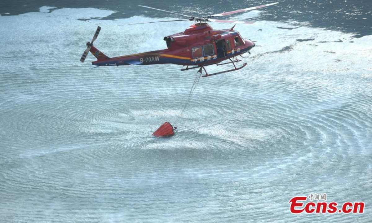 2022 年 8 月 19 日，一架直升机扑灭了重庆市涪陵区的大规模山火。消防员奋力扑灭大火。 图片：中新社