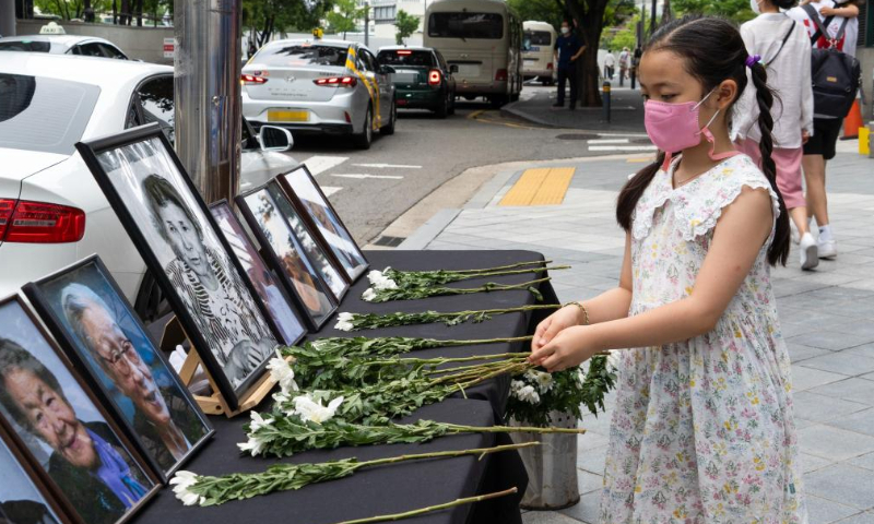 A child presents flowers to portraits of comfort women in Seoul, South Korea, Aug. 14, 2022. Comfort women refer to victims forced into sexual slavery by Japanese troops during World War II. The day of Aug. 14 was designated the International Memorial Day for Comfort Women in 2012 by the 11th Asian Alliance Conference for Comfort Women.. Photo: Xinhua