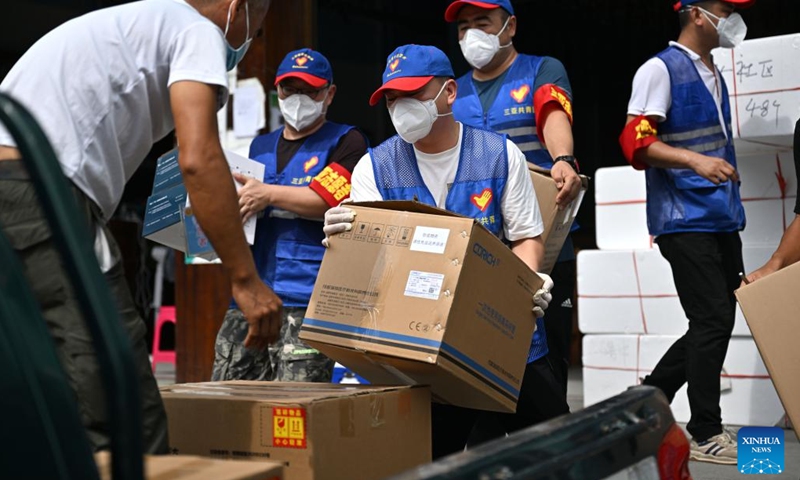 Chen Yi (C), a tourist-turned volunteer from Wenzhou in east China's Zhejiang Province, helps to carry medical supplies at a storehouse in Sanya, south China's Hainan Province, Aug. 9, 2022. Amid the latest resurgence of COVID-19 in Sanya, some tourists have joined local volunteers in combating the epidemic.(Photo: Xinhua)