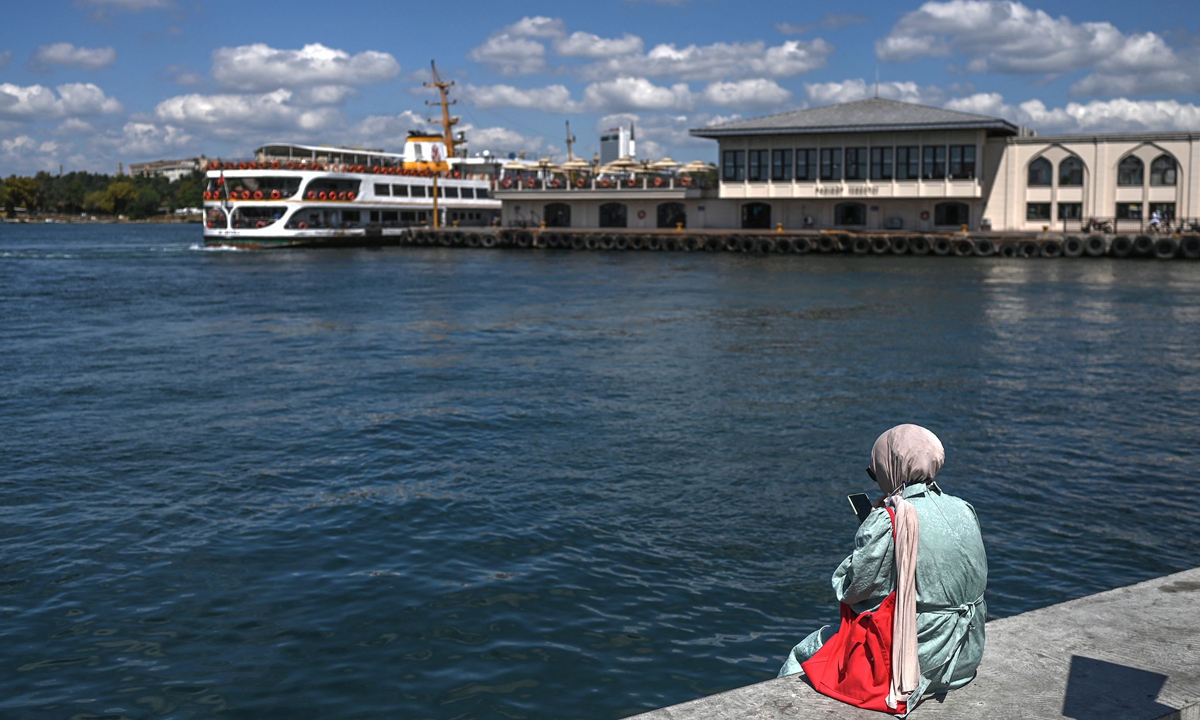 A resident sits on a dock in front of a ferry boat in the port of Kadikoy on the northern shore of the Sea of Marmara in Istanbul, Turkey on August 21, 2021. Photo: AFP