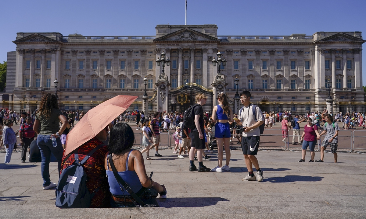 Tourists shelter from the sun under an umbrella as they sit on the stairs of Queen Victoria Memorial in London on August 11, 2022. Heatwaves and prolonged dry weather are damaging landscapes, gardens and wildlife, the National Trust has warned. Britain is braced for another heatwave that will last longer than July's record-breaking hot spell, with highs of up to 35 degrees Celsius expected next week. Photo: VCG