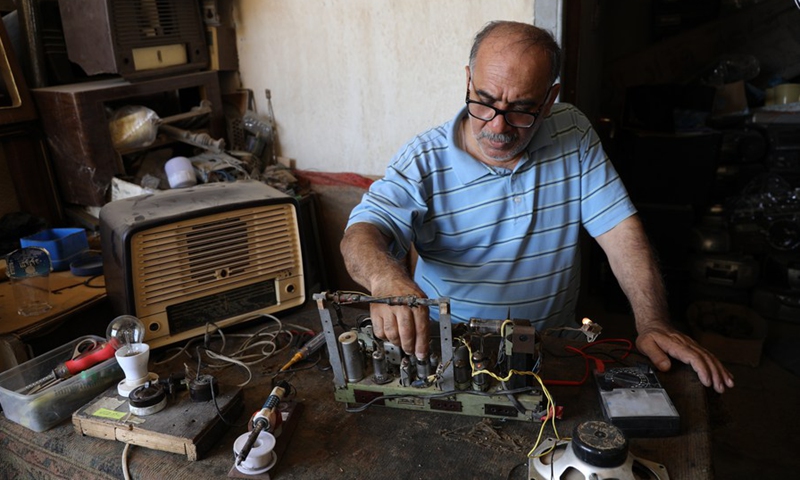 Fuad Hashim, owner of a radio repair shop, works on an antique radio in his workshop in central Baghdad, Iraq, on July 29, 2022. (Photo: Xinhua)