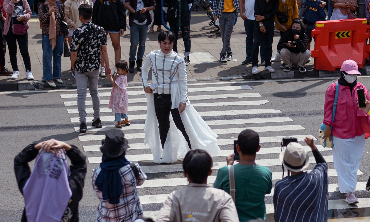 A crowd look on as Indonesian youths present self-styled fashion creations at a pedestrian crossing-turned-catwalk in Jakarta, Indonesia on July 24, 2022. Photo: AFP
