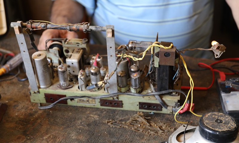 Fuad Hashim, owner of a radio repair shop, works on an antique radio in his workshop in central Baghdad, Iraq, on July 29, 2022.(Photo: Xinhua)