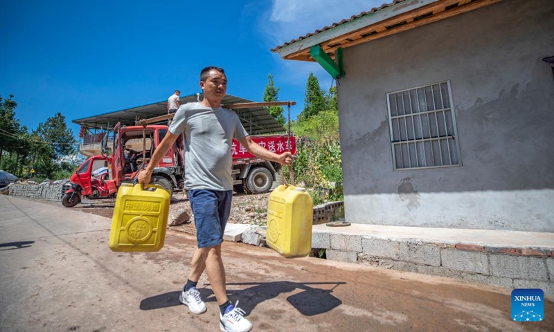 A staff member fetches water for housebound villagers in Luoping Village of Wushan County, southwest China's Chongqing, Aug. 13, 2022. Persistent heatwaves have led to drought in parts of Wushan County. Authorities have increased efforts to better manage water resources for drought relief and ensure water supply for locals. (Xinhua/Huang Wei)