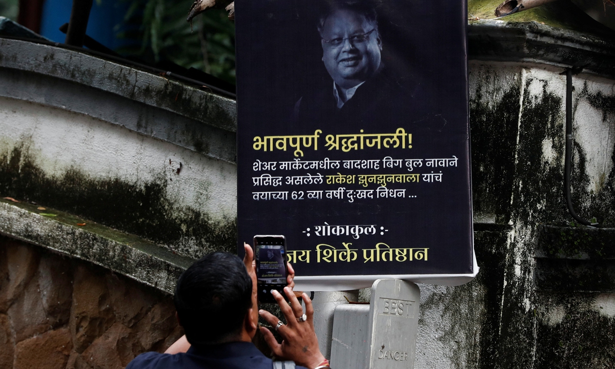 A security guard takes a picture of a poster paying tribute to the late Indian billionaire Rakesh Jhunjhunwala outside his residence after he passed away earlier today in Mumbai, India, August 14, 2022. Photo: IC