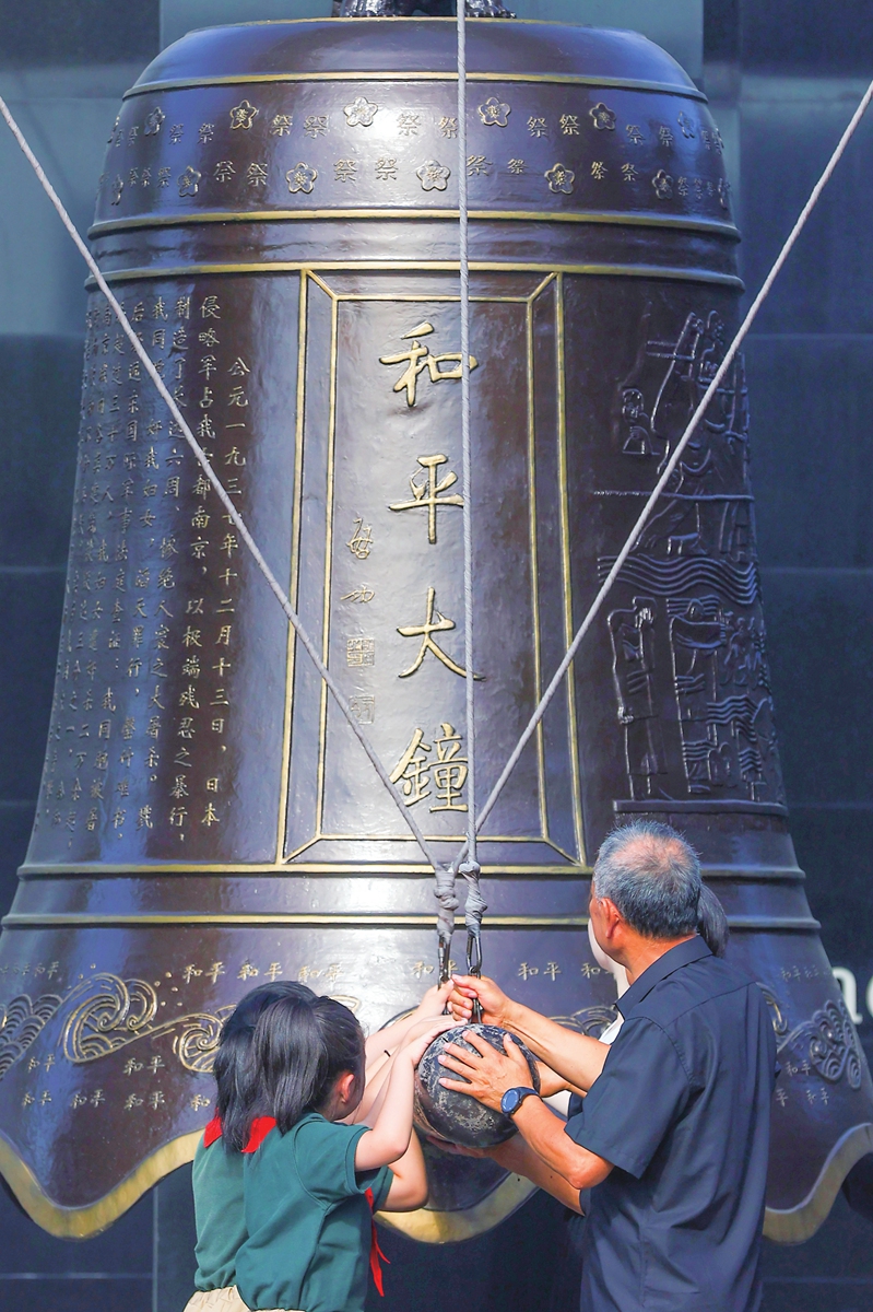 Representatives of descendants of the survivors of the Nanjing Massacre strike the Peace Bell with local students at the Memorial Hall of the Victims of the Nanjing Massacre by the Japanese Invaders in Nanjing, East China's Jiangsu Province. The memorial hall held the event 