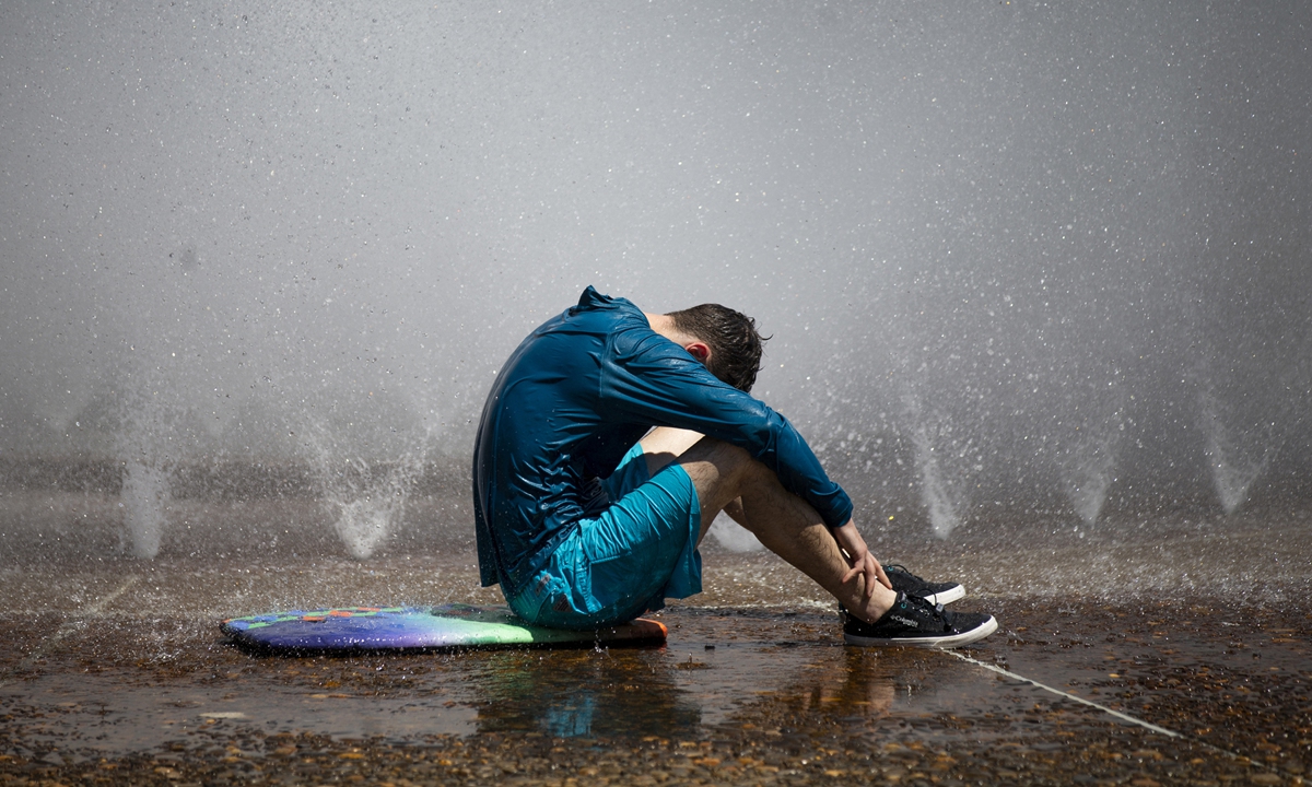 A man cools off next to the Salmon Street Springs fountain in downtown Portland, Oregon, on July 26, 2022. Photo: VCG